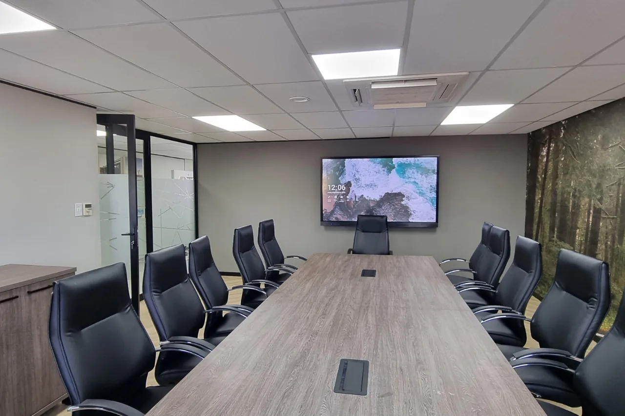 A modern conference room equipped with a large screen and multiple chairs set up for a meeting.