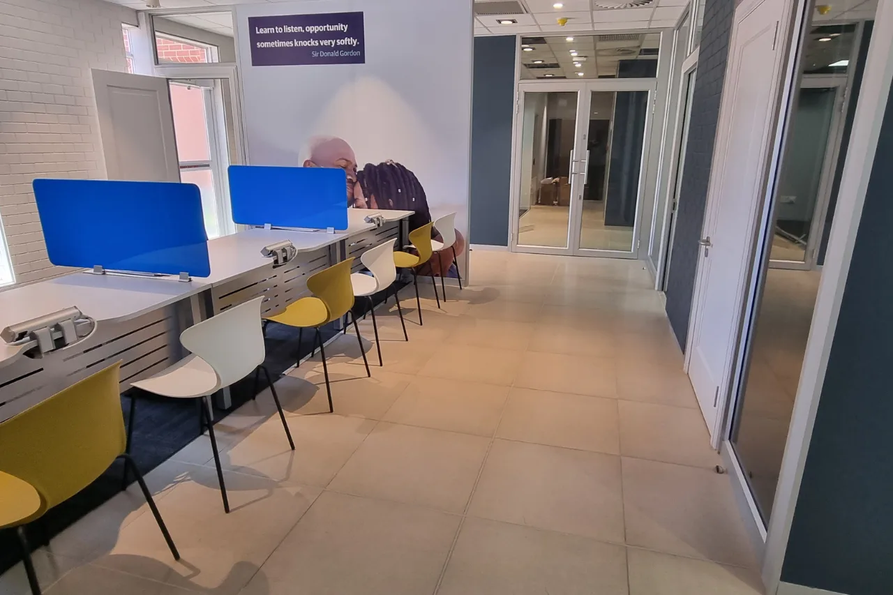 A hallway with a help desk and chairs, designed for customer service interactions.
