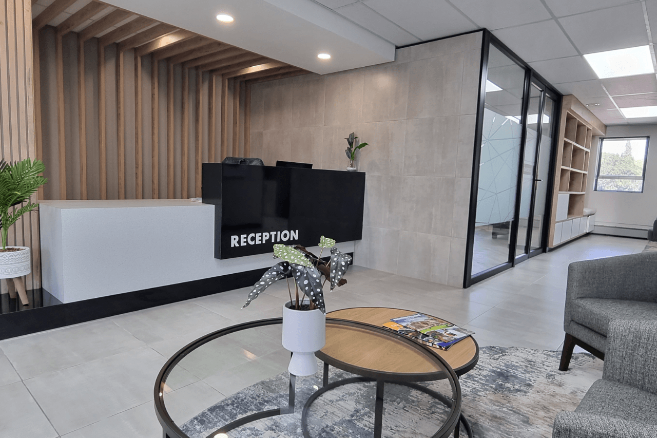 Office reception area with a spacious waiting area, including a large table surrounded by chairs for guests.