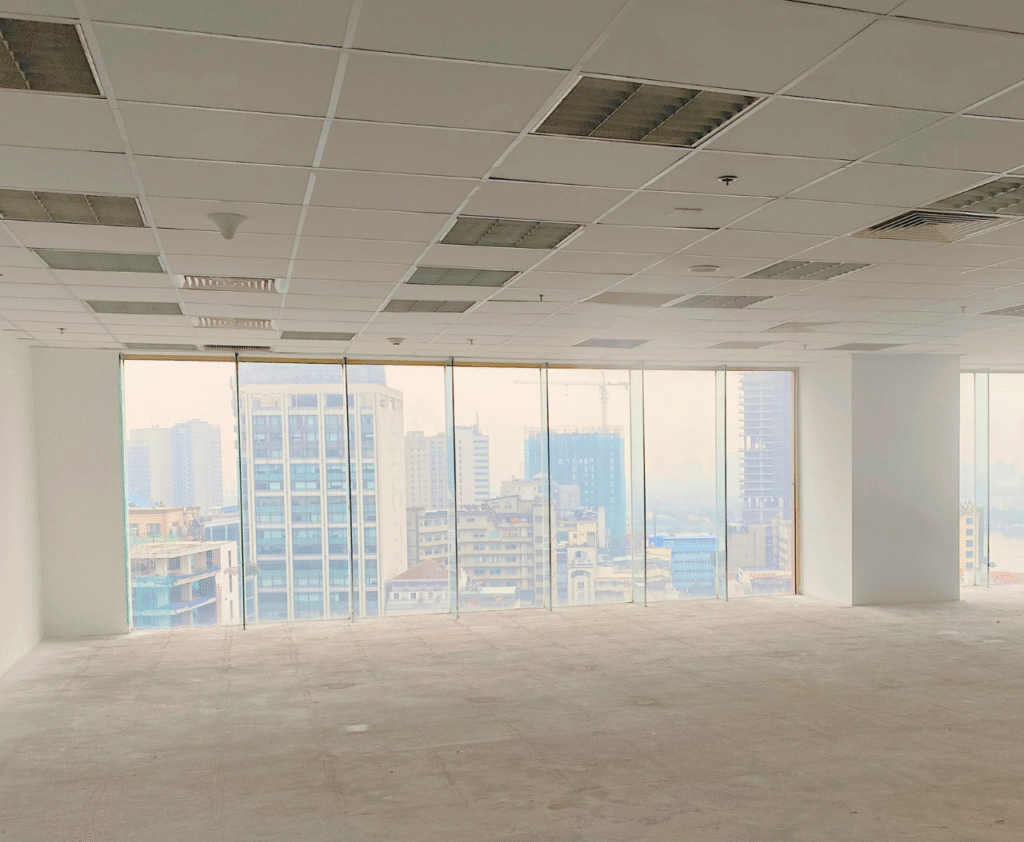 Unoccupied office with floor-to-ceiling windows offering a view of the cityscape.
